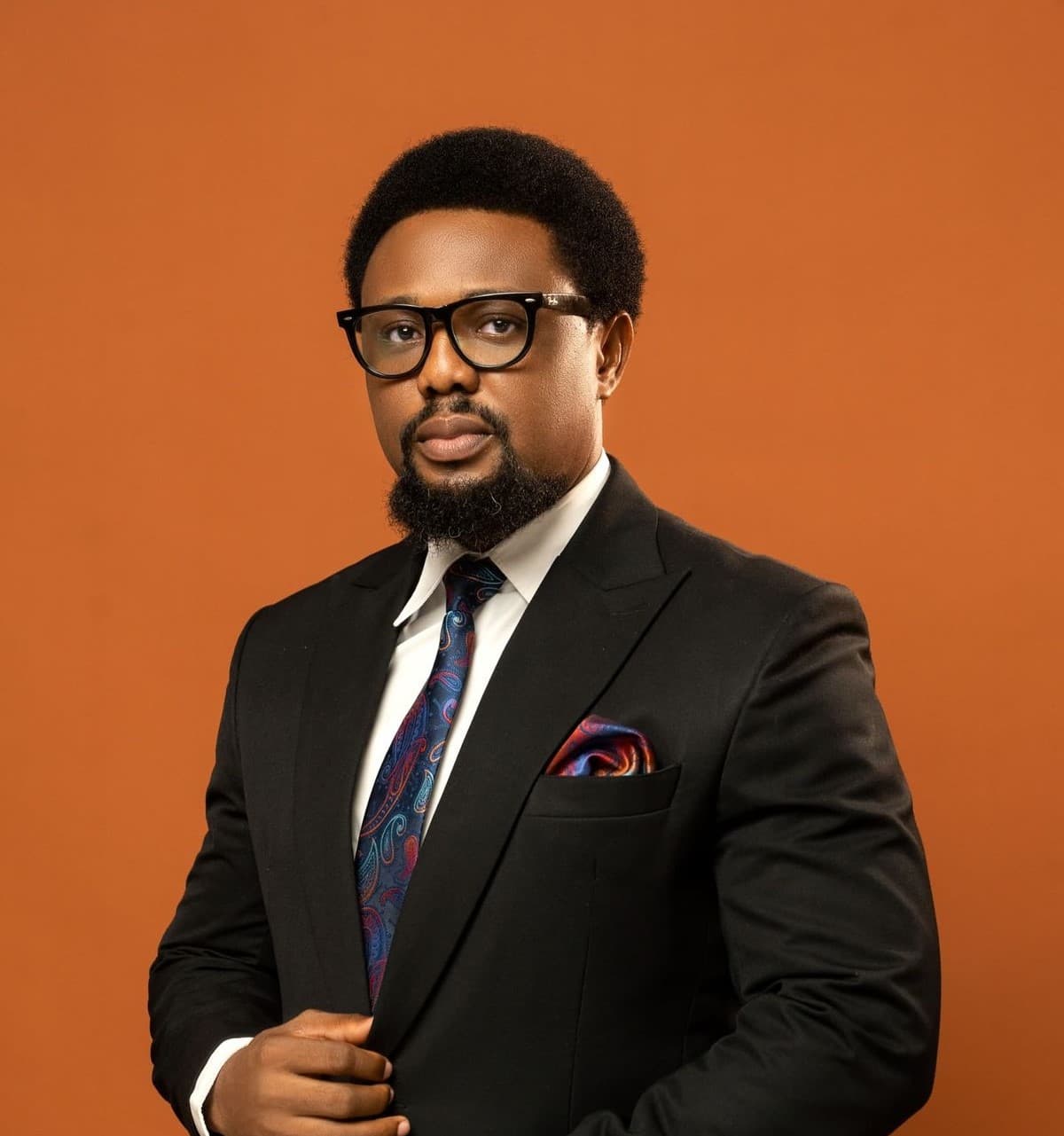 Photo originale : portrait d'un homme en costume noir et lunettes, sur fond orange